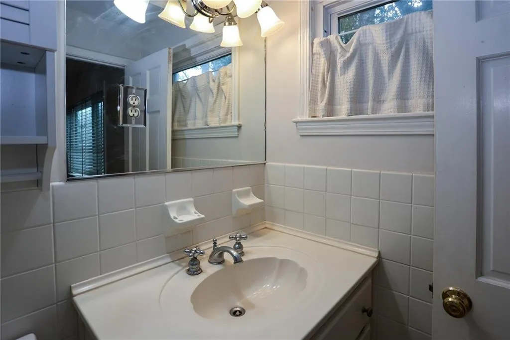 Full Bathroom with vanity, a shower, tile walls, and healthy amount of natural light
