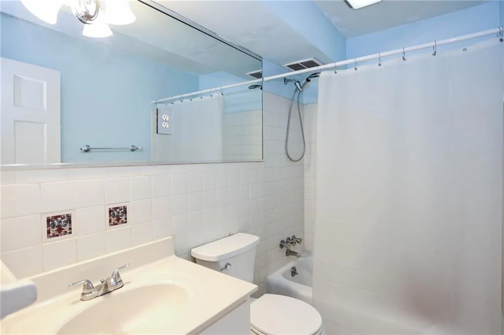 Full bath featuring vanity, tile walls, and shower/ tub combo