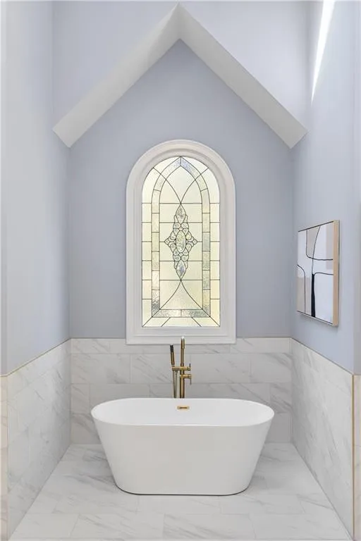 Bathroom featuring tile walls, a freestanding bath, wainscoting, and marble finish flooring