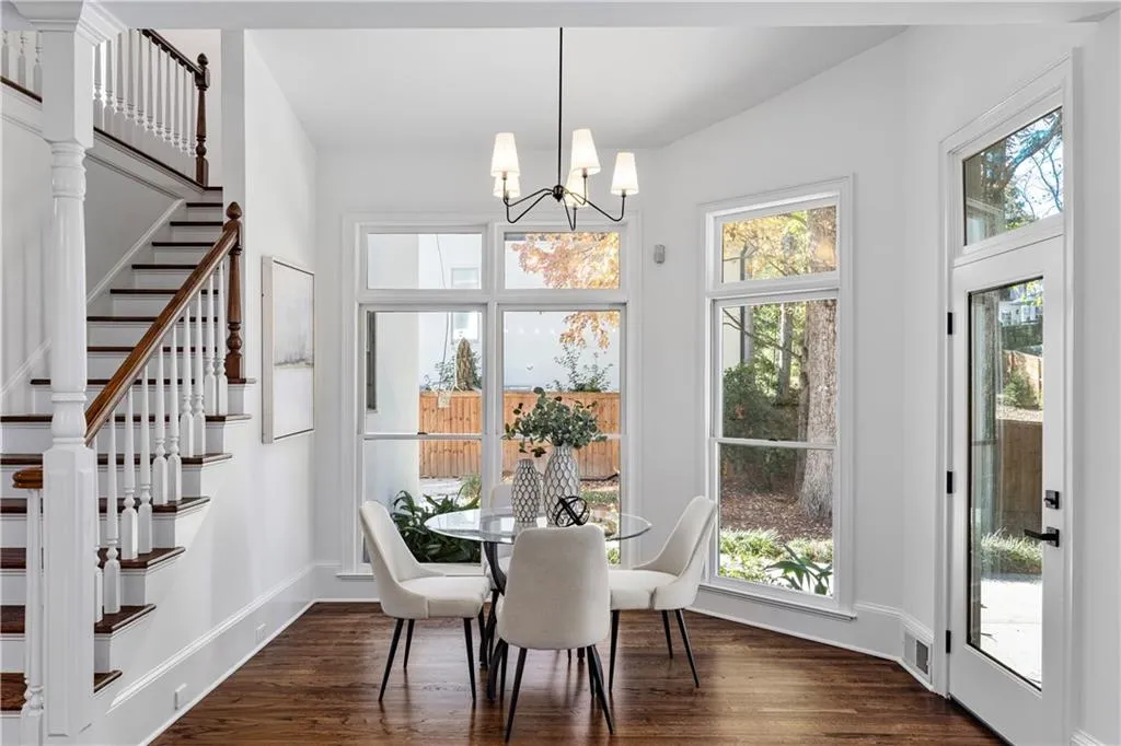 Dining room with dark wood finished floors, healthy amount of natural light, stairway, and a chandelier