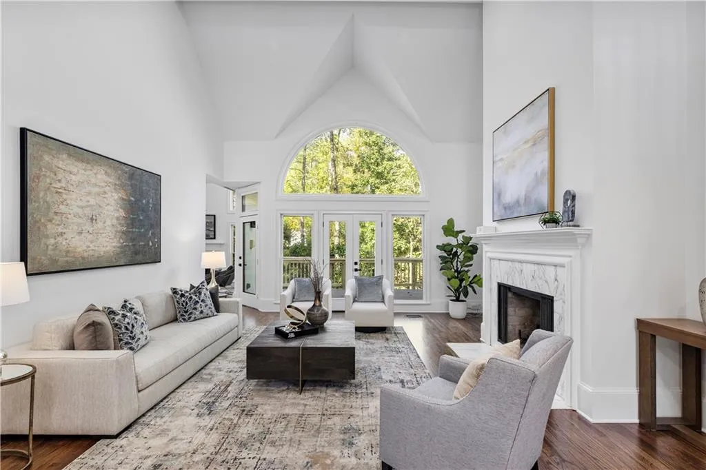 Living room with high vaulted ceiling, a high end fireplace, dark wood-style floors, and french doors