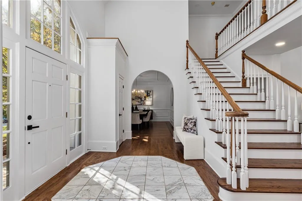 Entrance foyer featuring arched walkways, dark wood finished floors, a high ceiling, stairway, and ornamental molding