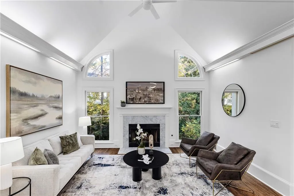 Living room featuring high vaulted ceiling, a high end fireplace, wood finished floors, and ceiling fan