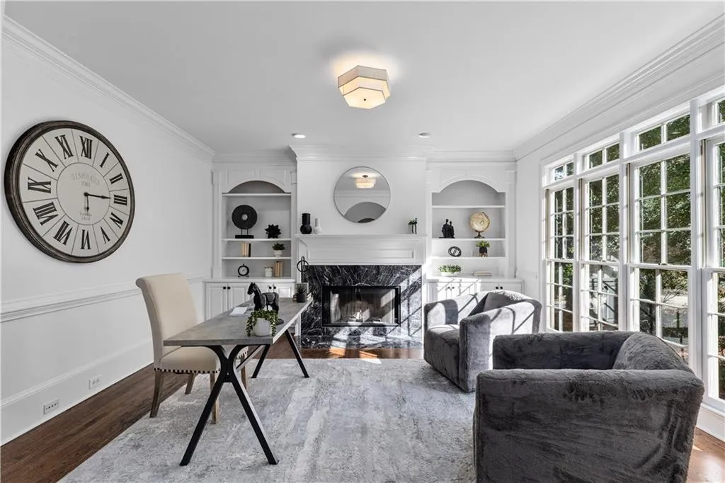 Office space with crown molding, wood finished floors, a fireplace, and built in shelves