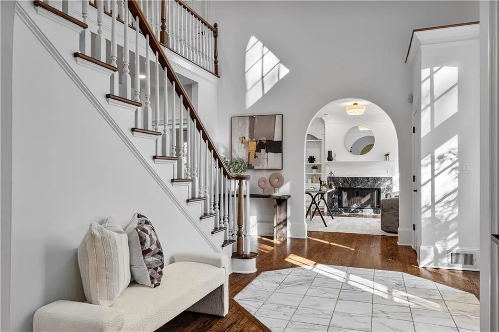 Foyer entrance featuring a high ceiling, a fireplace, stairs, wood finished floors, and arched walkways