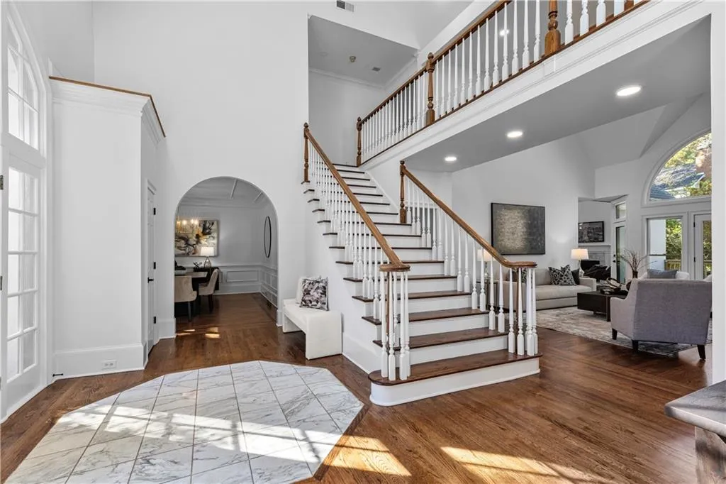Foyer entrance featuring arched walkways, a high ceiling, dark wood finished floors, stairs, and recessed lighting