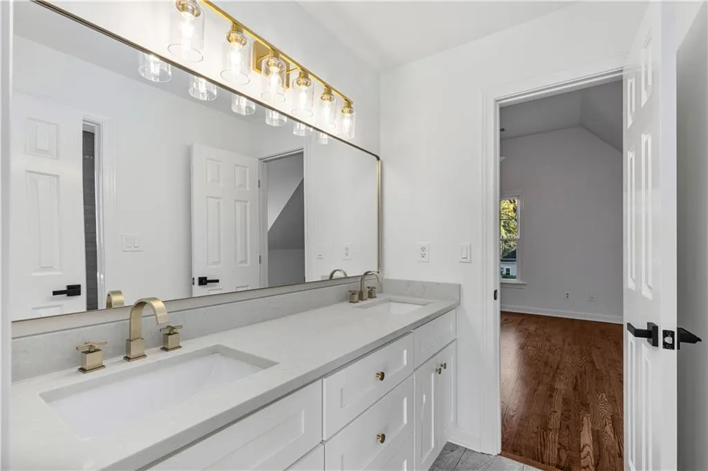 Bathroom with double vanity and light wood-style flooring