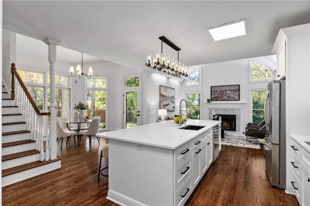 Kitchen with open floor plan, white cabinets, decorative light fixtures, and an island with sink