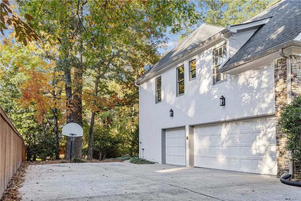 View of property exterior featuring stone siding, roof with shingles, a garage, and stucco siding