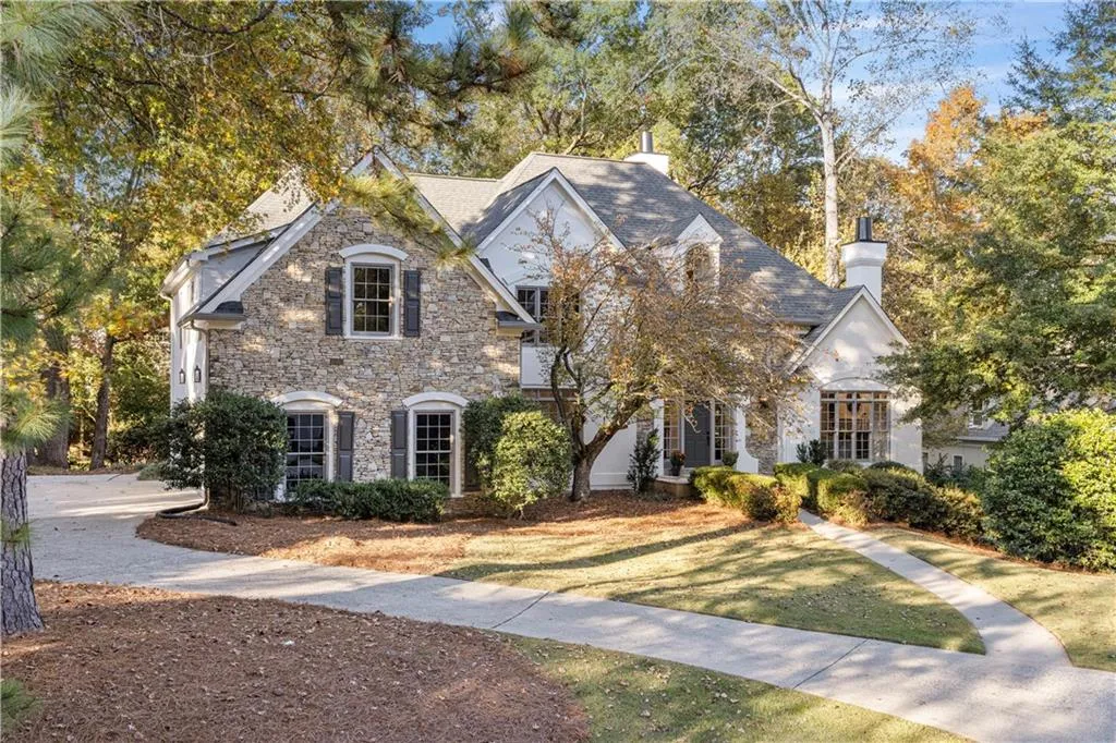 View of front of house with a chimney, stone siding, and a front lawn