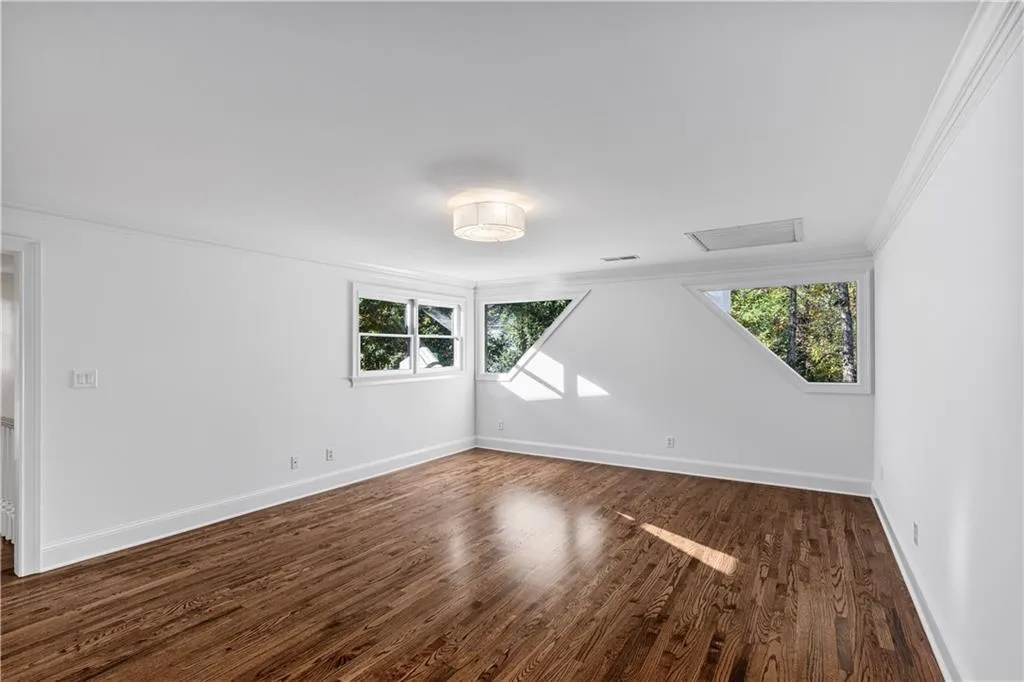 Unfurnished room with dark wood-type flooring and crown molding