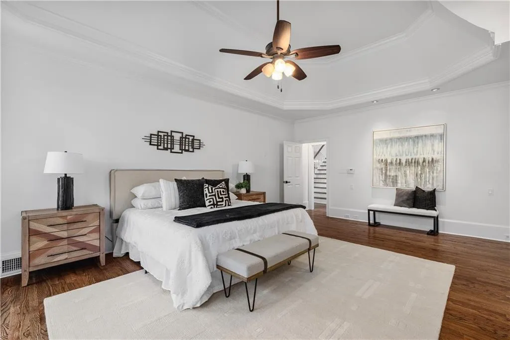 Bedroom with crown molding, a tray ceiling, dark wood-type flooring, and ceiling fan