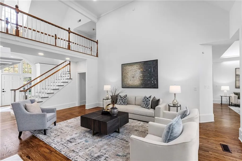 Living room with high vaulted ceiling, wood finished floors, and stairs