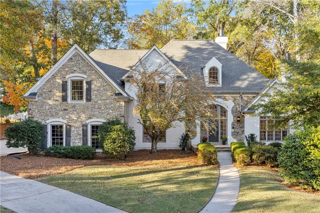 View of front of property with a chimney, stone siding, and a front lawn