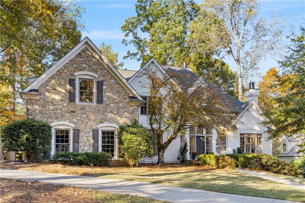 View of front of house featuring a chimney, a front yard, and stone siding