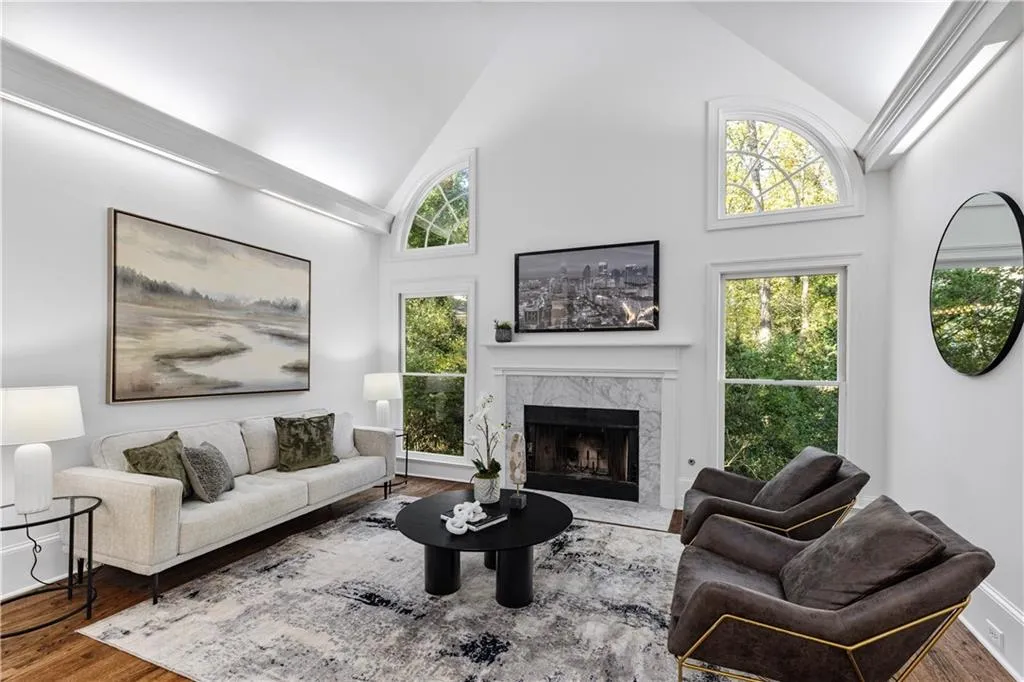 Living room featuring high vaulted ceiling, wood finished floors, and a premium fireplace