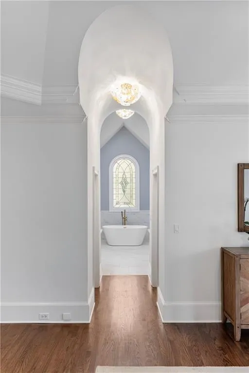 Hall with lofted ceiling, crown molding, and wood finished floors
