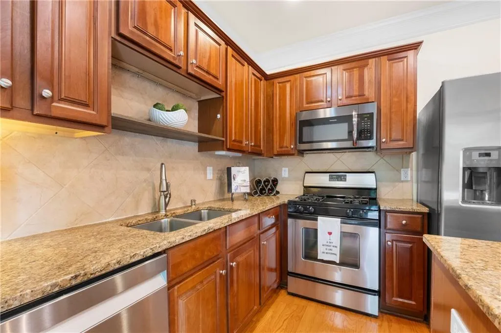 Kitchen view with light stone counters and backsplash, range with gas cooktop