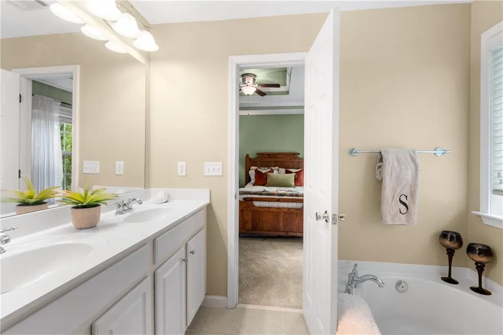 View of primary ensuite bath with soaking tub, double vanity and separate shower, with view to the bedroom