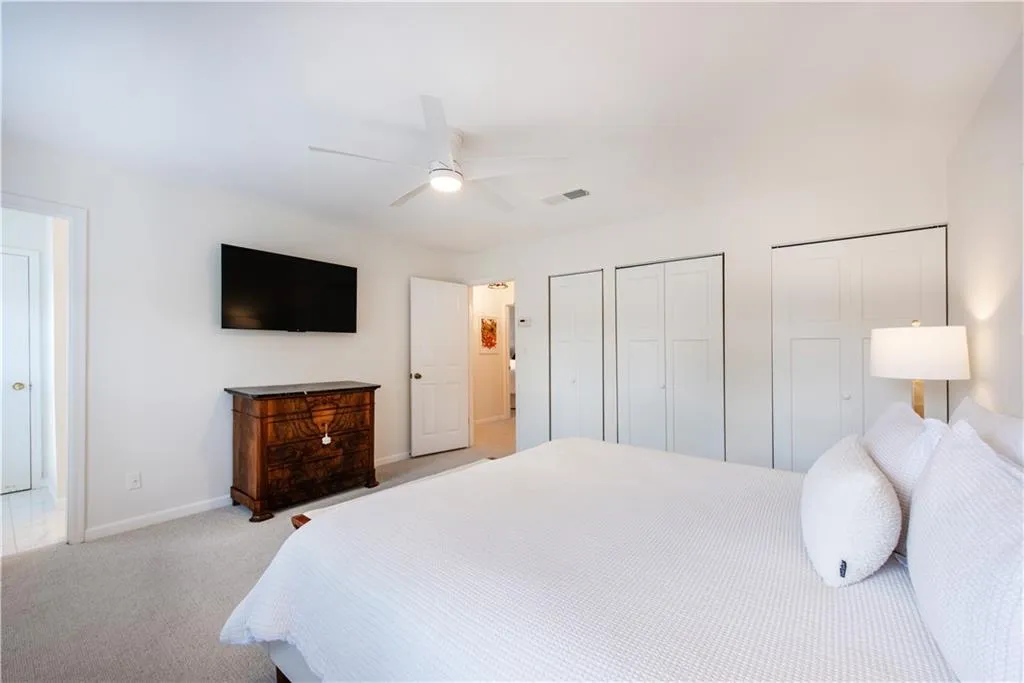 Bedroom featuring light carpet, multiple closets, and a ceiling fan