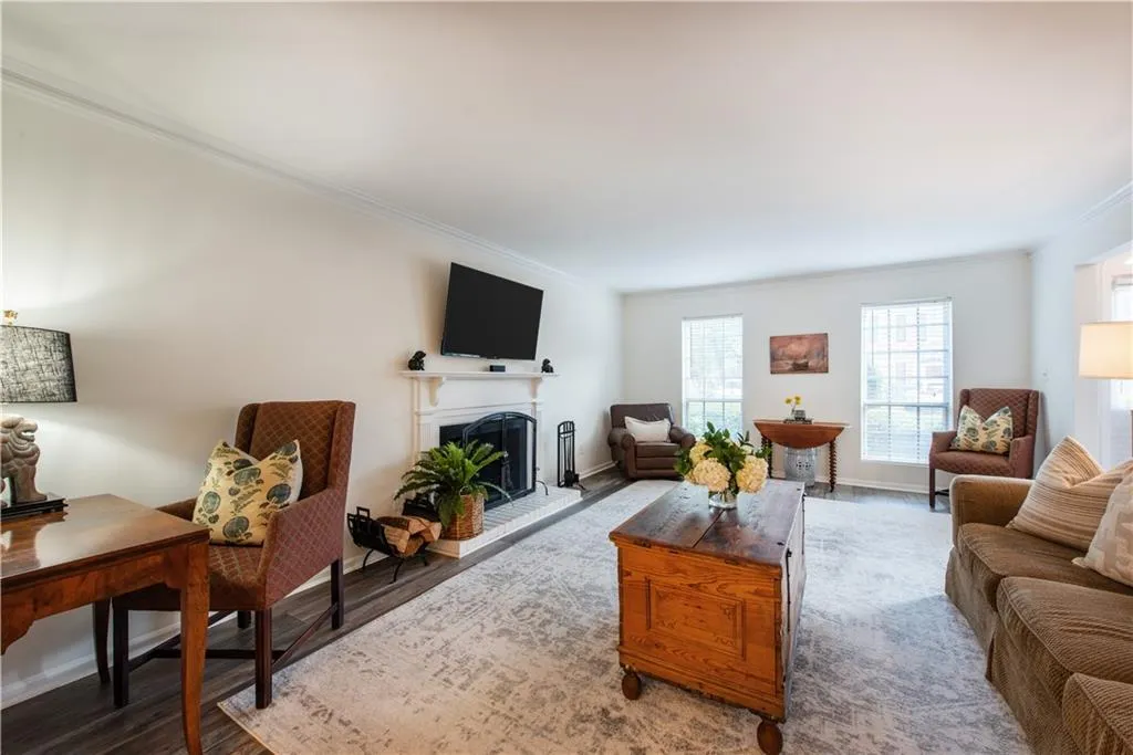 Living room featuring crown molding, a fireplace with raised hearth, and wood finished floors