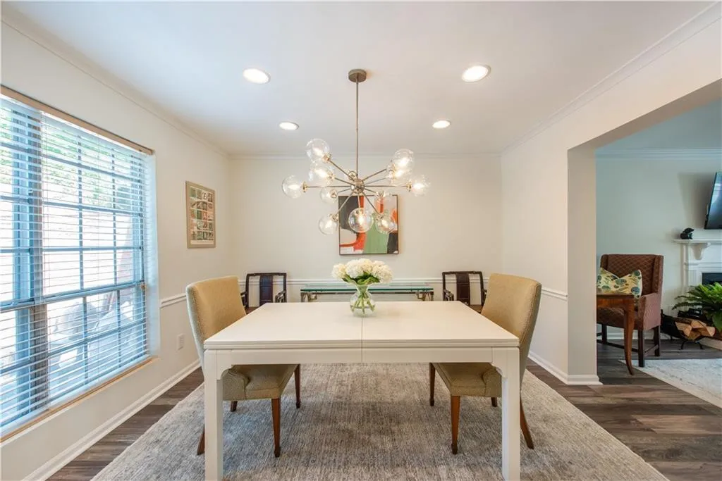 Dining space with dark wood-type flooring, recessed lighting, ornamental molding, and a chandelier