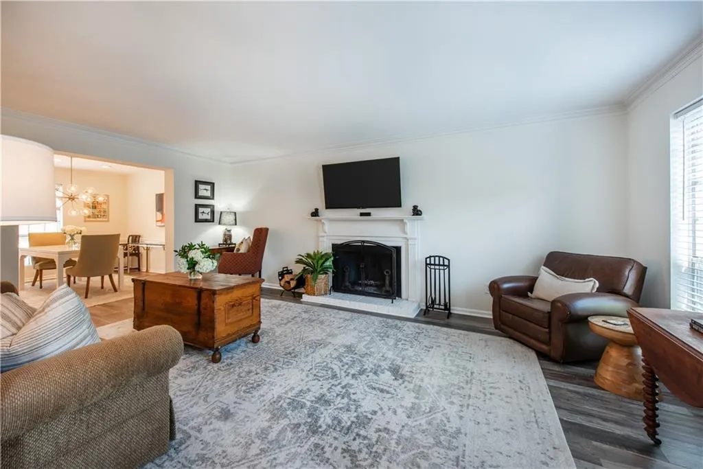 Living area featuring a chandelier, crown molding, wood finished floors, and a fireplace with raised hearth