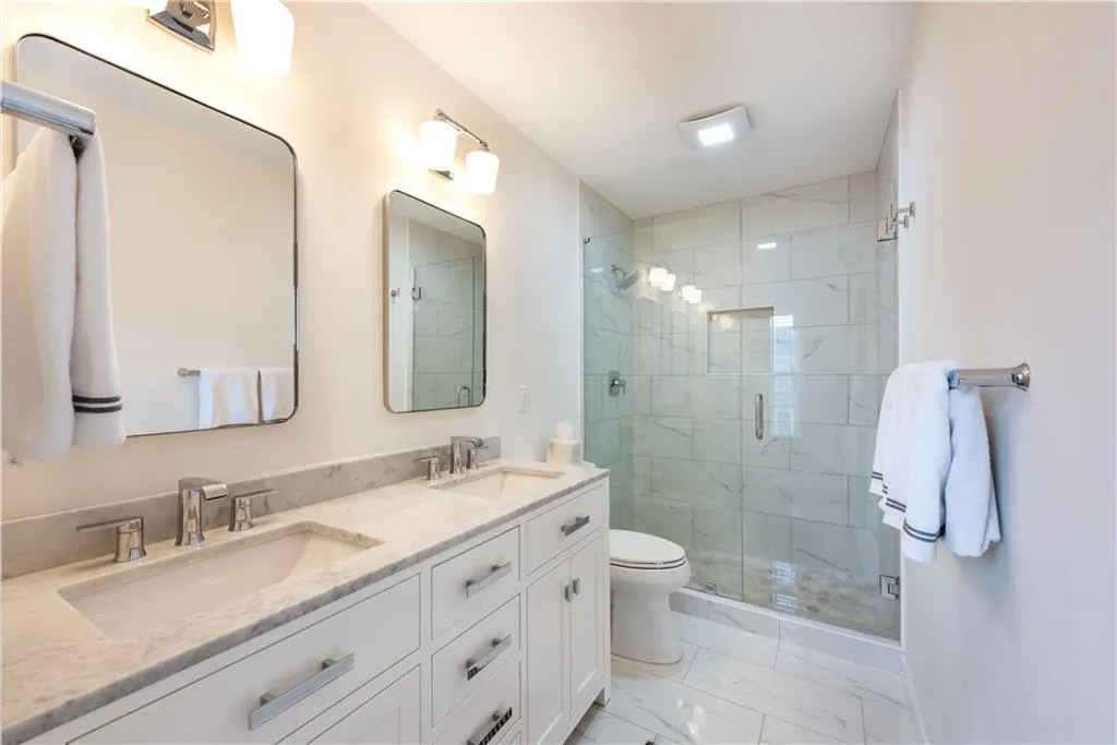 Bathroom featuring marble look tiles, a shower stall, and double vanity