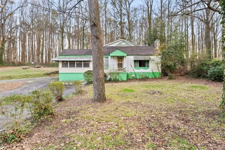 View of front of house with a chimney, a front yard, and covered porch