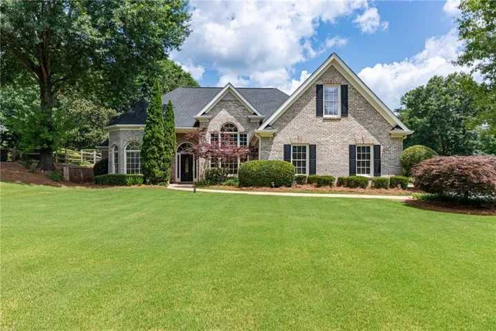 Brick exterior featuring black shutters and a prominent arched entryway