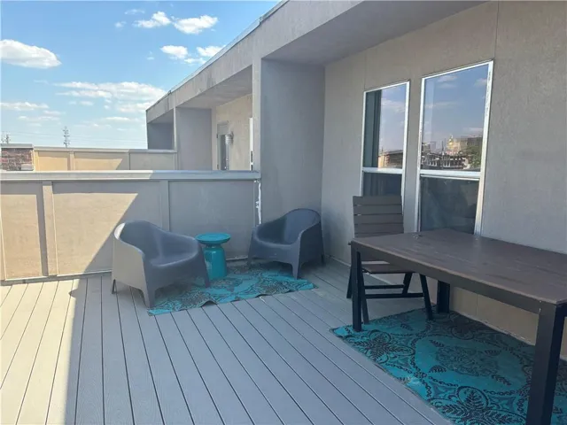 Rooftop deck featuring composite decking, a stucco-finish privacy wall, and two large windows