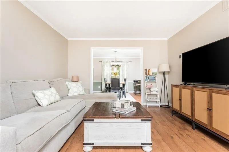 Living room featuring light hardwood / wood-style floors, an inviting chandelier, and ornamental molding