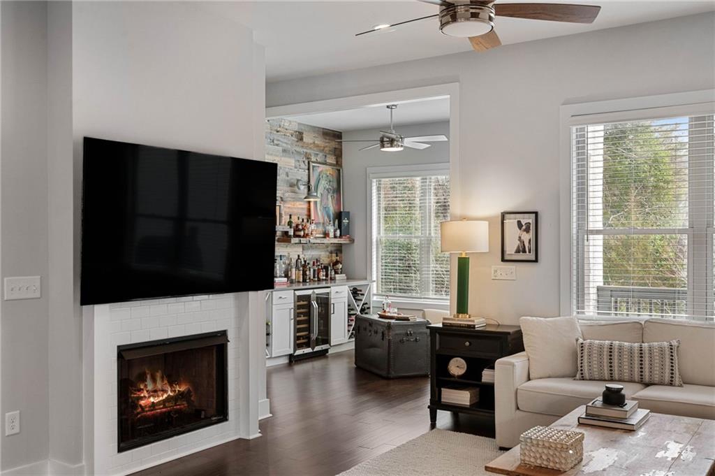 Living room featuring dark wood-type flooring, a healthy amount of sunlight, ceiling fan, and beverage cooler