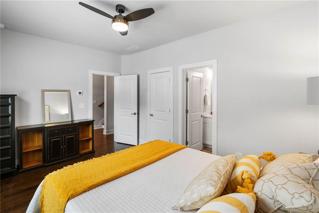Bedroom with dark hardwood / wood-style flooring, ensuite bathroom, and ceiling fan
