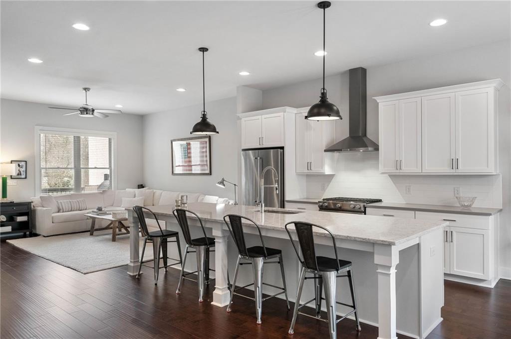 Kitchen with hanging light fixtures, a kitchen island with sink, dark hardwood / wood-style floors, and wall chimney exhaust hood