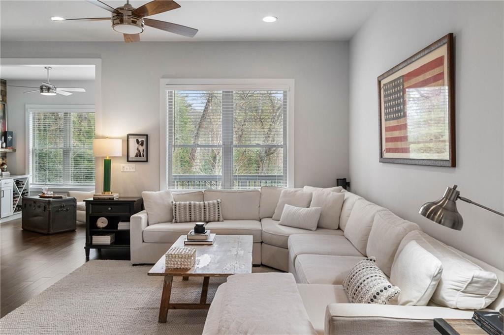 Living room with a healthy amount of sunlight, dark hardwood / wood-style floors, and ceiling fan