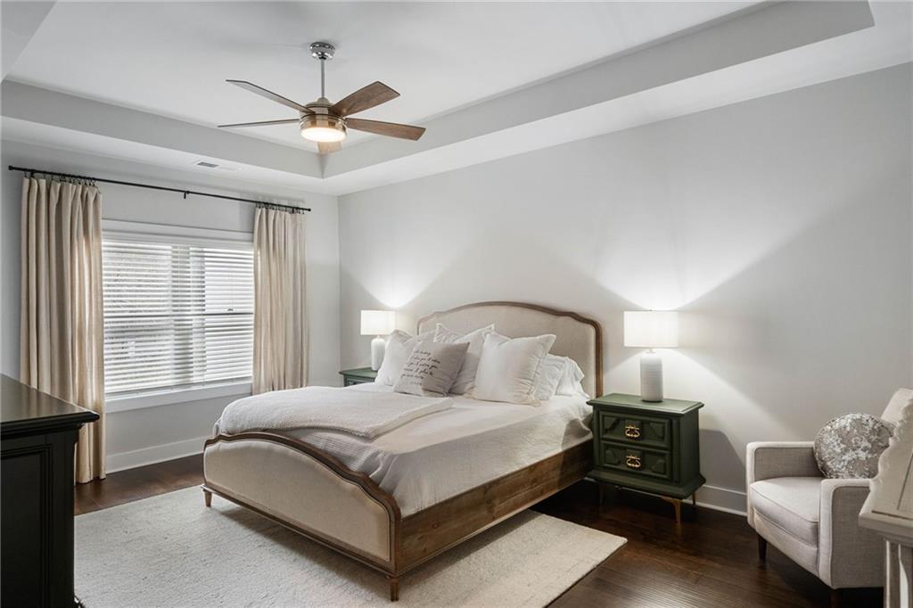 Bedroom with ceiling fan, a raised ceiling, and dark hardwood / wood-style flooring