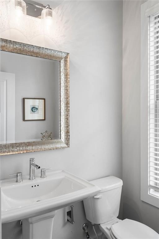 Bathroom featuring toilet, a healthy amount of sunlight, and sink