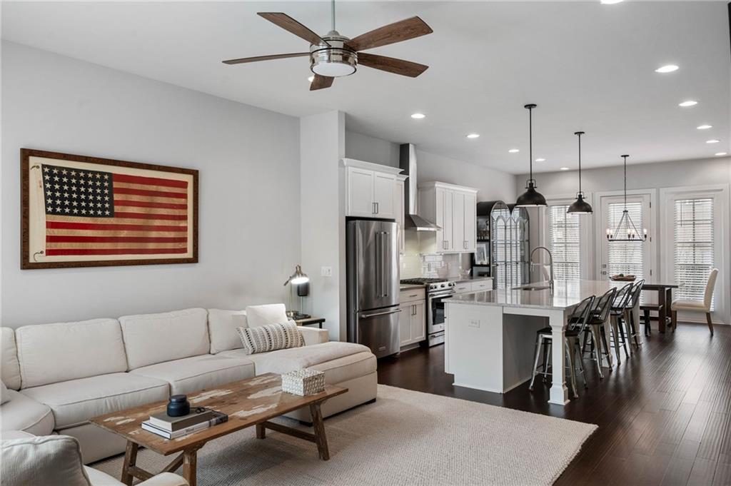Living room with dark hardwood / wood-style floors, ceiling fan, and sink