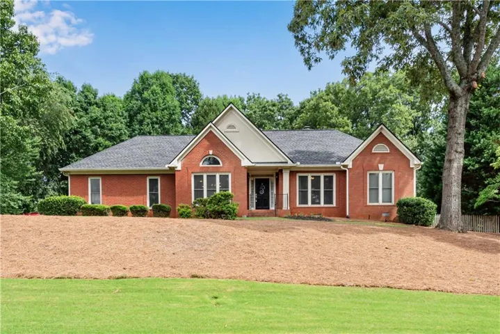 Red brick exterior, black shingle roof, mature tree, shrubbery, landscaped front yard