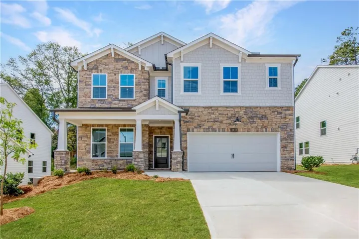 Craftsman-style home featuring stone siding, concrete driveway, covered porch, an attached garage, and a front yard