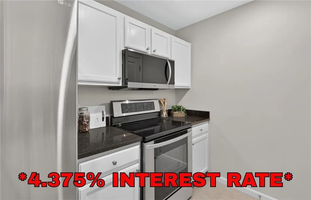 Kitchen featuring white cabinetry, dark countertops, a stainless steel electric range, and an over-the-range microwave