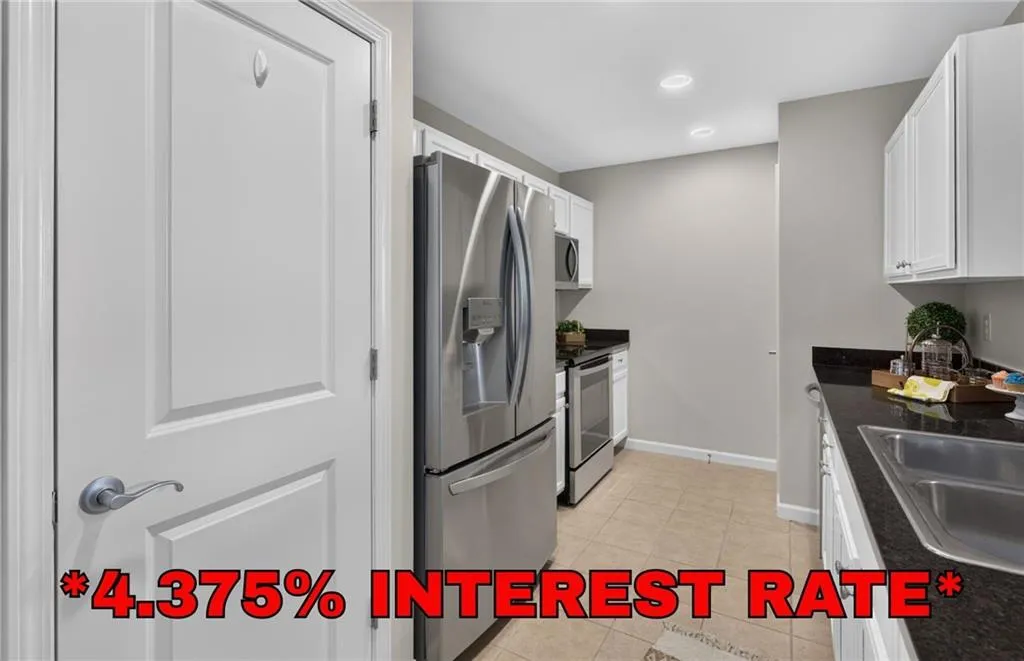Kitchen featuring stainless steel appliances, white cabinetry, dark countertops, a double basin sink, and tile flooring