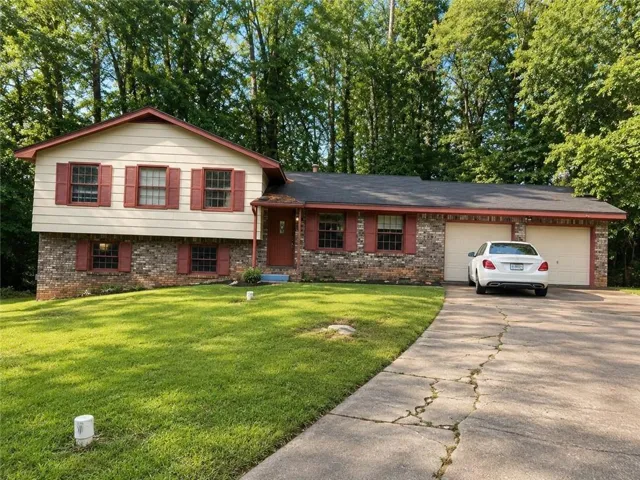 Split-level residence featuring brick and siding exterior, a two-car garage, and a concrete driveway