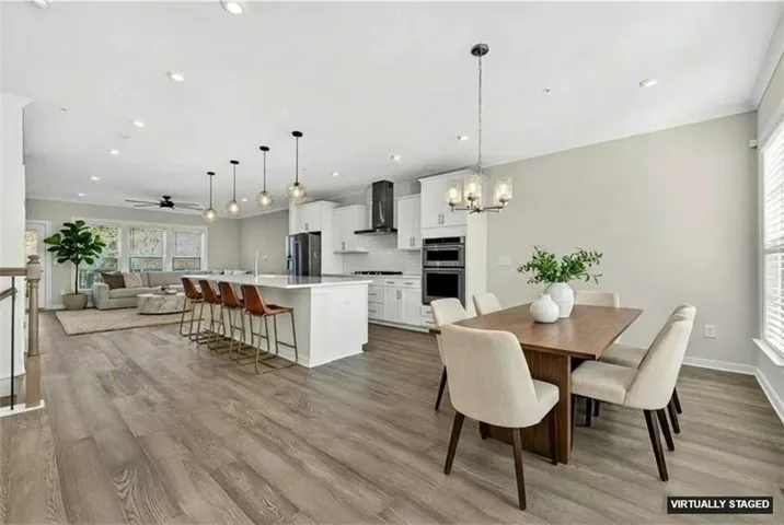 Dining area with ceiling fan, light wood-type flooring, a chandelier, recessed lighting, and ornamental molding