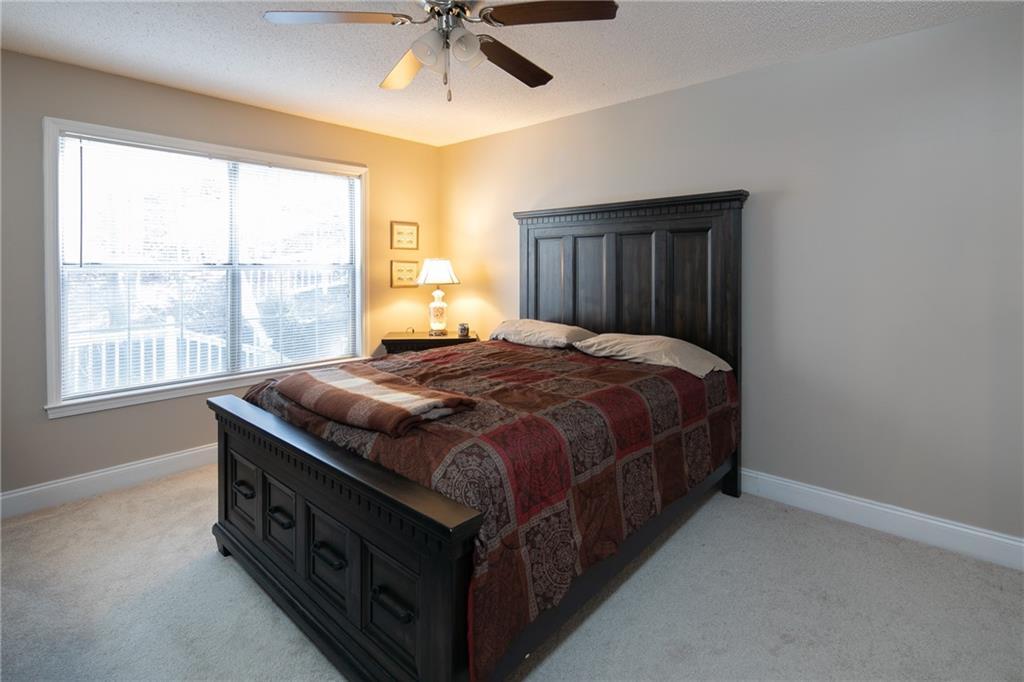 Carpeted bedroom featuring ceiling fan and a textured ceiling