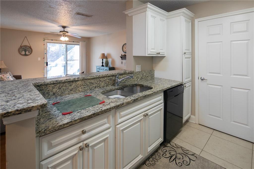 Kitchen featuring white cabinets, ceiling fan, light stone countertops, sink, and kitchen peninsula