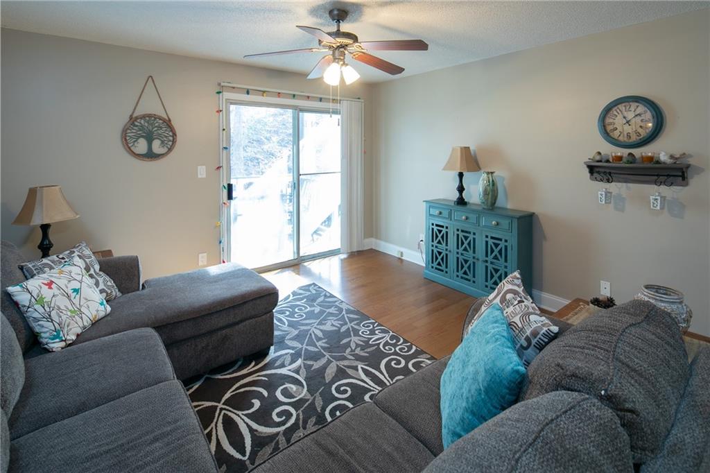Living room with ceiling fan, a textured ceiling, and wood-type flooring