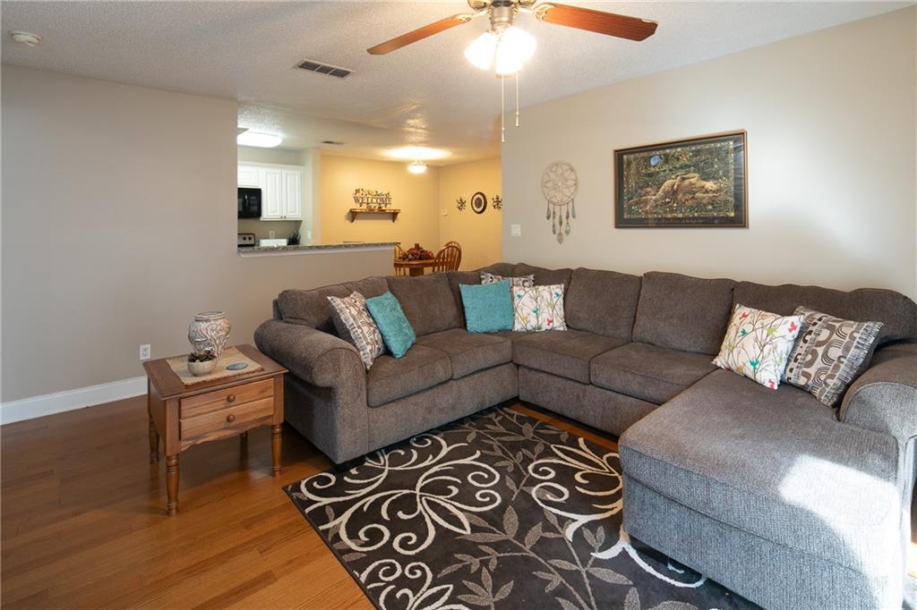 Living room featuring hardwood / wood-style flooring, ceiling fan, and a textured ceiling