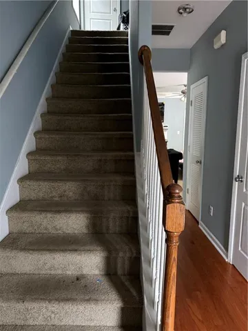 Carpeted stairway with a wooden handrail and white balusters